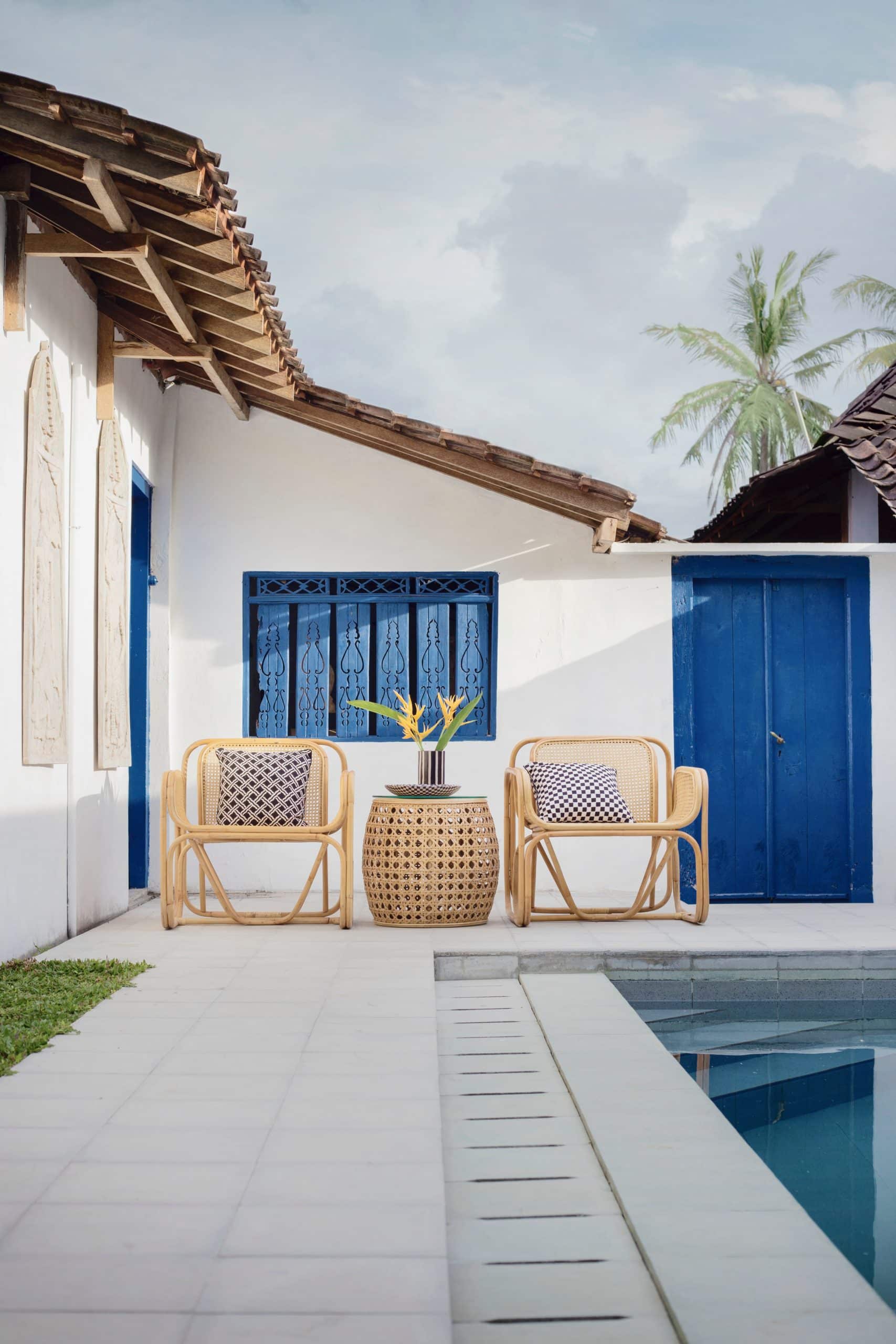 terrasse blanche avec piscine et mobilier extérieur en rotin