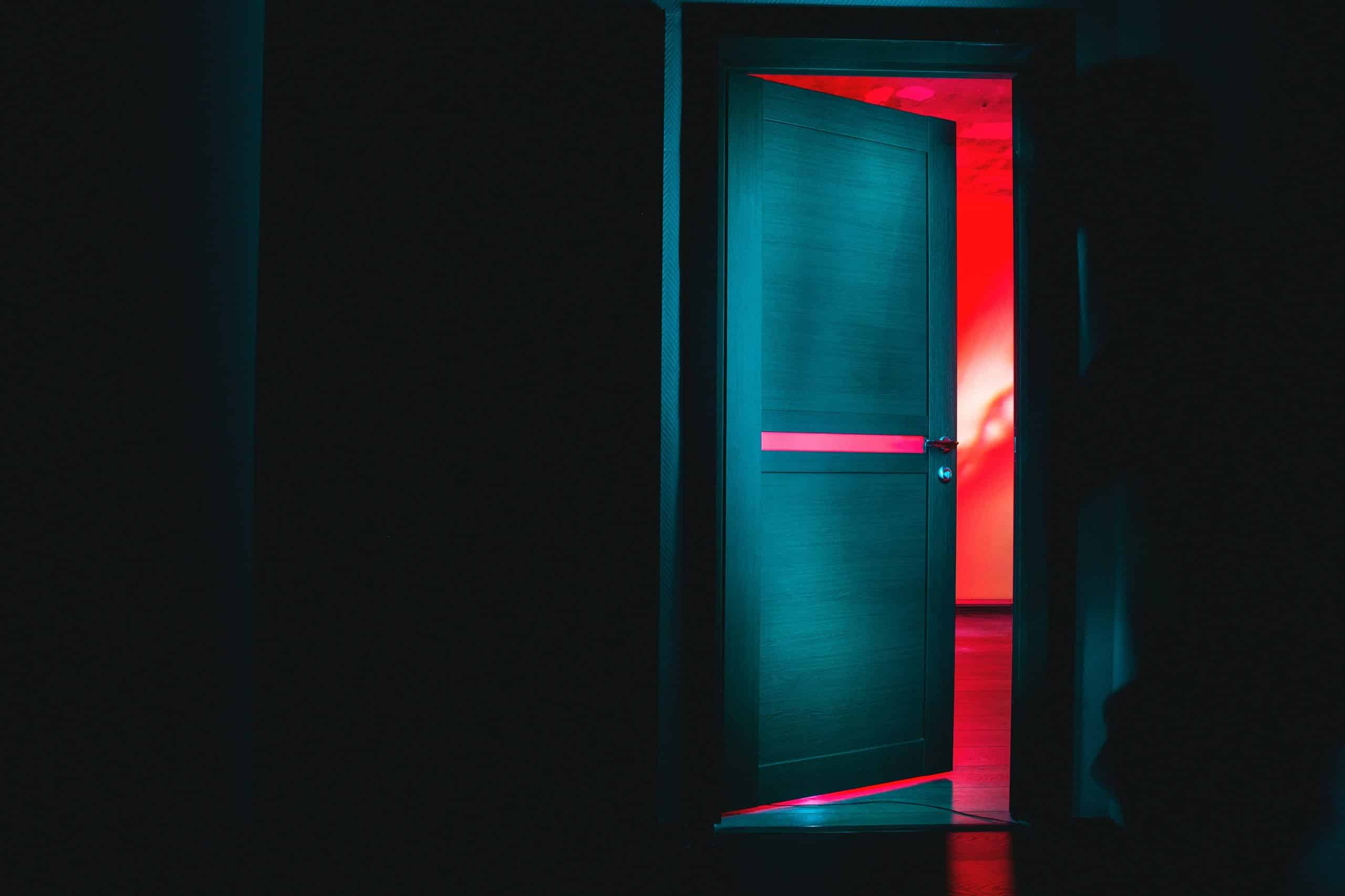 Porte ouverte dans le noir avec lumière rouge