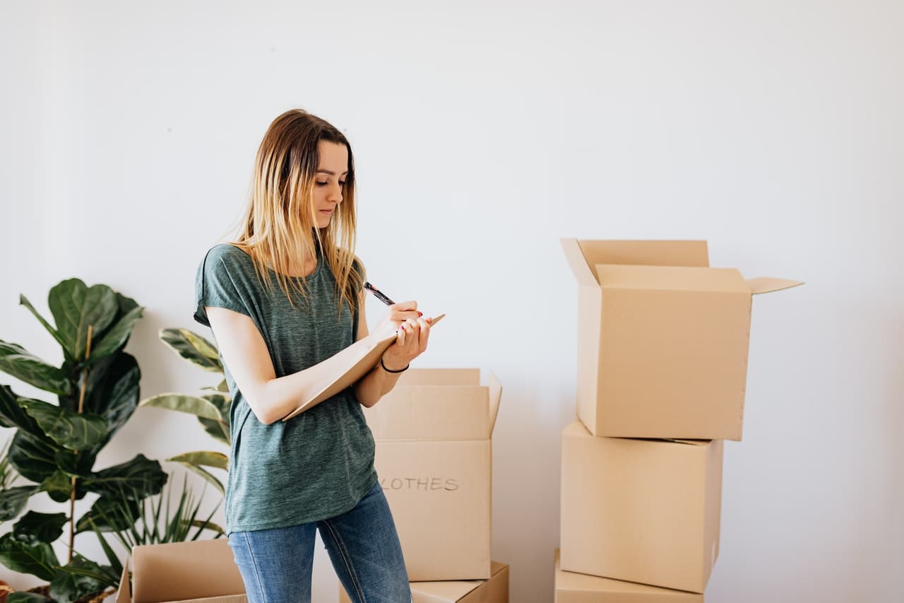 femme qui fait une liste devant des cartons